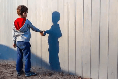 Ett barn som pekar på sin skugga på en vägg.
