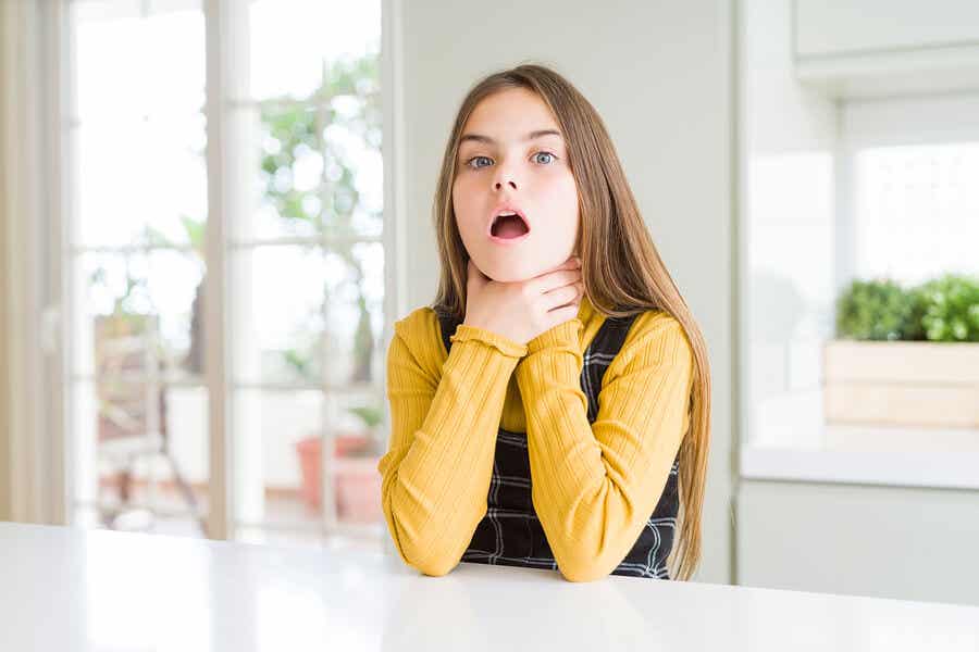 En flicka med dysfagi som håller i sin hals.