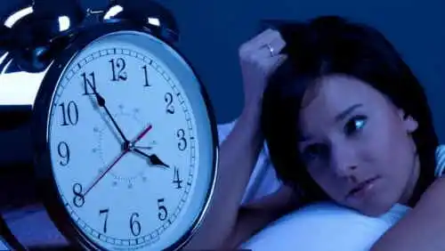 Kvinna som inte kan sova tittar på klockan.