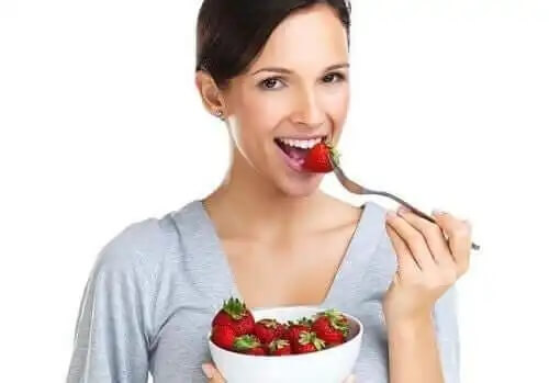 En kvinna som äter en jordgubbe
