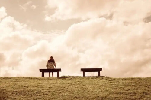 En kvinna som sitter ensam på en bänk på ett krön..