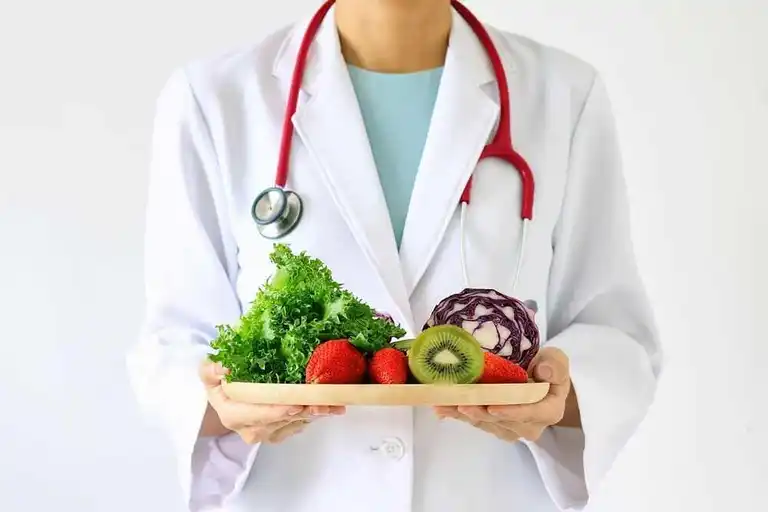 Nutritionist håller i en bricka med grönsaker och frukt.
