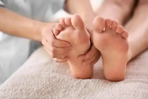 Person masserar sina egna fötter.