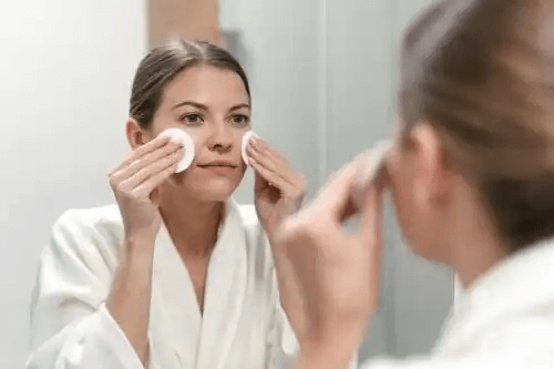 Kvinnan rengör huden på kinderna
