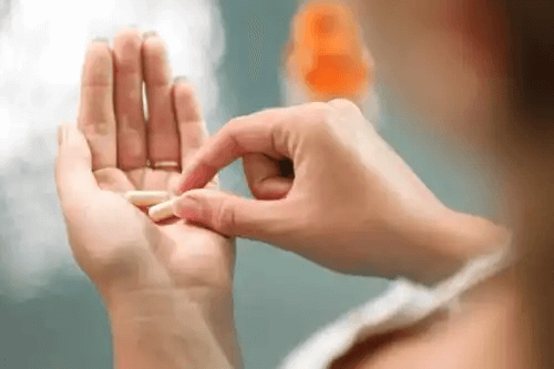 En person som håller två piller.