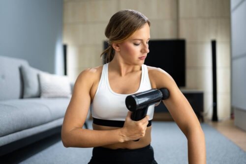 En kvinna använder en massagepistol.