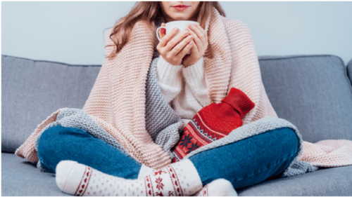 kvinna med pläd och tekopp i soffa